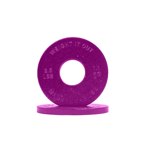 A purple circular Cast Iron Machined Weight Plate Pair from Weight It Out, marked 2.5 LBS and 1.1 KG, stands upright on another plate against a white background—precision-machined for Olympic bars with minimal weight variance.