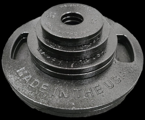A stack of black Weight It Out Cast Iron Weight Plate Sets of various sizes, with MADE IN THE USA embossed on the largest plate, arranged on a black background. Perfect for customizing your home gym setup.
