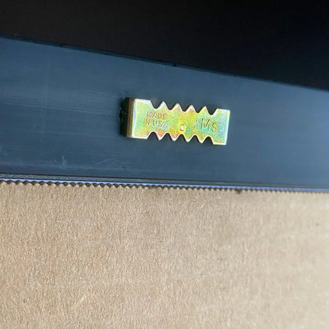 Close-up of the back of the Cat Fist poster by Skinny Petes Gourmet Catnip, featuring a yellow sawtooth hanger labeled “MADE IN USA © AMS” above a cardboard backing.