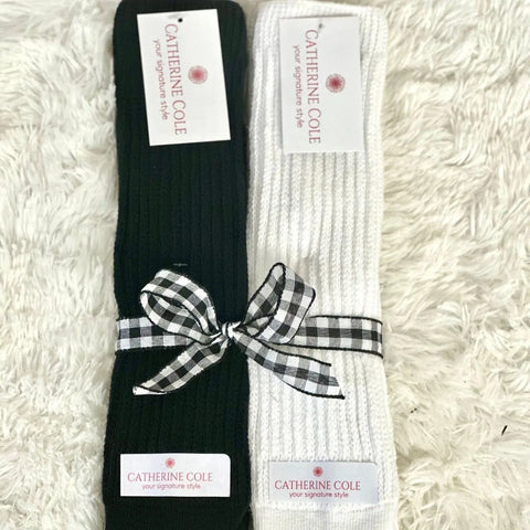 The Catherine Cole 2 Pairs Bundle ULTIMATE Slouch Socks includes one black and one white pair, wrapped with a black-and-white checkered ribbon and signature style labels—perfect for 80s and 90s fashion fans.