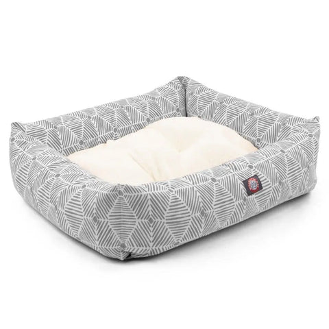 The Charlie Luxe Bagel Bed by Majestic Pet features raised sides, a soft cream cushion, gray geometric outer fabric, and a red and white logo patch. The cover is machine washable for easy care.