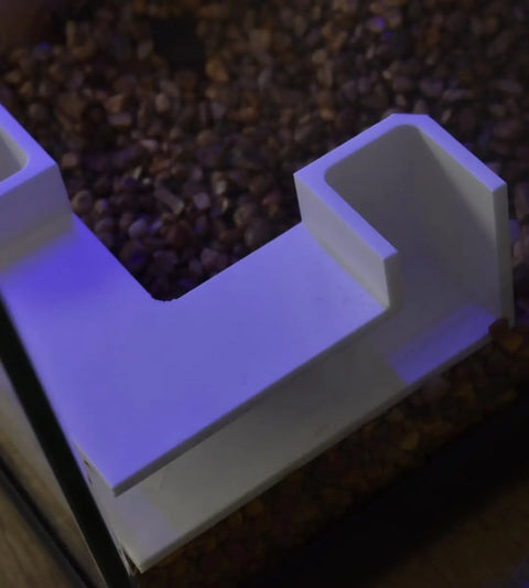 The Chatelet Aquarium Underground Tunnel by Chatelet Manufacturing is a unique fish and shrimp hideout that sits on the aquarium edge, filled with brown pebbles and blue light for standout decor. Made in the USA.