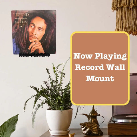 A Chatelet Groovy Now Playing Vinyl Record Wall Mount by Chatelet Manufacturing is displayed above a plant and turntable, holding a Bob Marley vinyl record. Text reads: Now Playing Record Wall Mount. Made in USA.