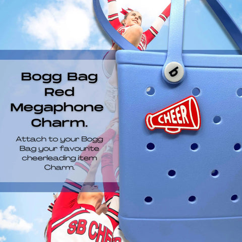 A blue Bogg Bag is decorated with the Chatelet Manufacturing BOGLETS Cheerleading Charm (Red Megaphone), a fun accessory compatible with Bogg Bags and other totes. Two cheerleaders in red and white SB CHEER uniforms cheer in the background.