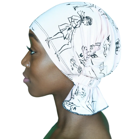 A person in profile wears the Chemo Beanies® Scarves - Stephanie—an elegant pale pink chemo headscarf with black abstract lines, tied at the back and fully covering the hair, while looking calmly ahead against a plain background.
