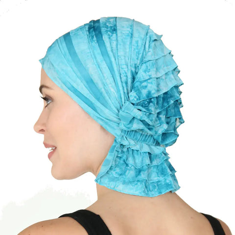 A woman smiles and looks to the side, wearing the Chemo Beanies® Molly— a textured, light blue chemo beanie by Chemo Beanies® that fully covers her hair. Shes paired it with a black tank top against a plain white background.