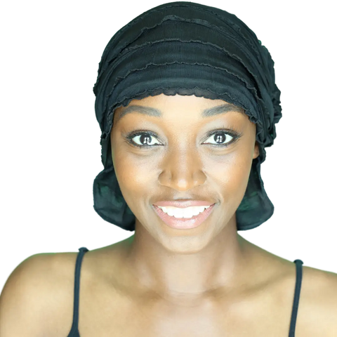 A smiling woman in a black Angelle Chemo Beanie® by Chemo Beanies® and a black strap top looks directly at the camera against a white background.