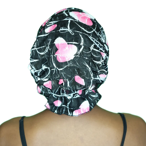 Person shown from behind wearing the Chemo Beanies® Delia— a black and pink patterned satin chemo beanie with white accents—paired with a black spaghetti strap top. Transparent background.