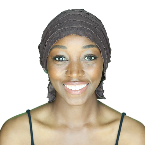 A smiling woman wears the Chemo Beanies® Janice scarf and a black spaghetti strap top, facing forward against a plain background.