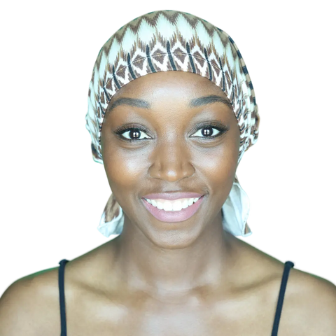 A smiling woman wears a Chemo Beanies® Roberta patterned chemo head cover and a black strap top, facing the camera against a plain background.