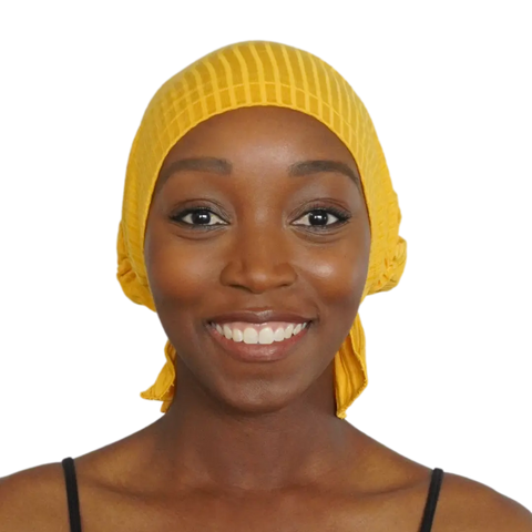 A smiling woman faces forward against a plain background, wearing the Chemo Beanies® Martha slip-on beanie in yellow with a black sleeveless top.