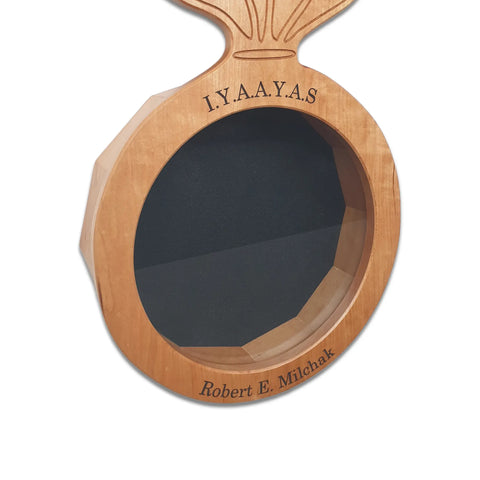 The Cherry Ammo Pisspot Shadow Box by Legacies of America Woodworking Company features a cherry hardwood plaque with a round recessed black center, engraved with I.Y.A.A.Y.A.S at the top and Robert E. Milchak at the bottom. Made in USA.