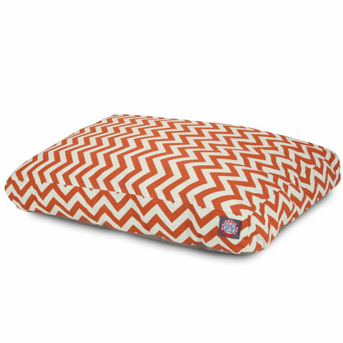 The Majestic Pet Chevron Rectangle Dog Bed features an orange and white zigzag chevron pattern, a small blue and red logo tag on the side, premium polyester fill, and is shown on a white background.