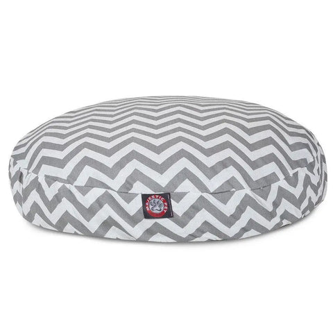 The Majestic Pet Chevron Round Dog Bed features a gray and white chevron pattern, a small red and white logo tag on the front, a soft cushioned design for comfort, and is washable for easy care.