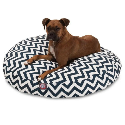 A brown dog with white markings relaxes on the Majestic Pet Chevron Round Dog Bed, featuring a black and white chevron pattern and washable cover, set against a plain white background.