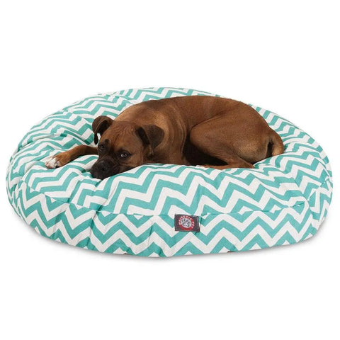A brown dog relaxes on the Majestic Pet Chevron Round Dog Bed, featuring a teal and white chevron pattern and a washable design.