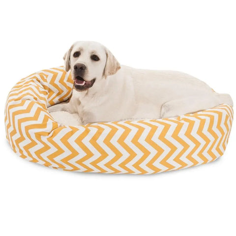 A light-colored Labrador is comfortably lying in the Majestic Pet Chevron Sherpa Bagel Dog Bed, which has a yellow and white chevron pattern and is made with water-resistant Outdoor Treated Polyester for durability.
