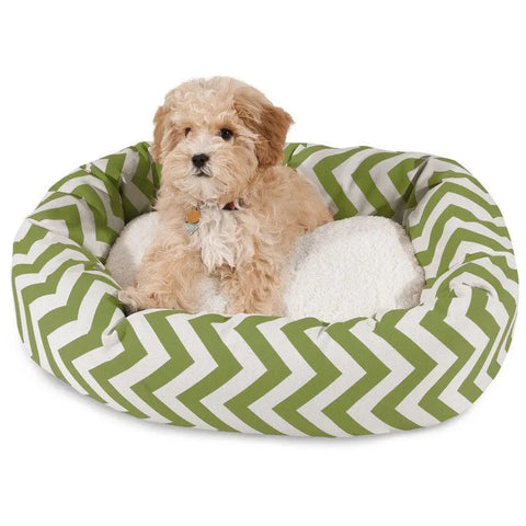 A small, fluffy, light brown dog rests comfortably on the white cushion of the Majestic Pet Chevron Sherpa Bagel Dog Bed, which features a green and white chevron pattern, water resistance, and spine support.