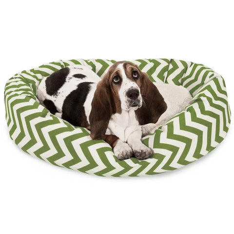A brown and white basset hound lies calmly on the Majestic Pet Chevron Sherpa Bagel Dog Bed, featuring a green and white water-resistant chevron pattern.