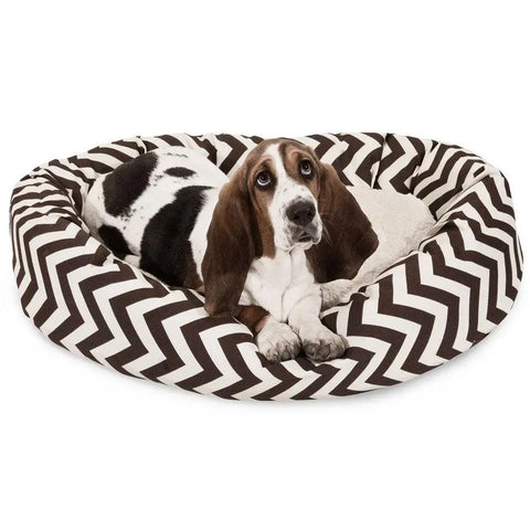 A brown and white basset hound relaxes in the Majestic Pet Chevron Sherpa Bagel Dog Bed, which features a black and white zigzag design and is made from outdoor treated polyester.