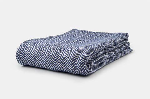 The Chevron Pattern Soft Wool Throw Size Blanket by American Blossom Linens, featuring a blue and white zigzag chevron design, is shown folded on a plain white background.