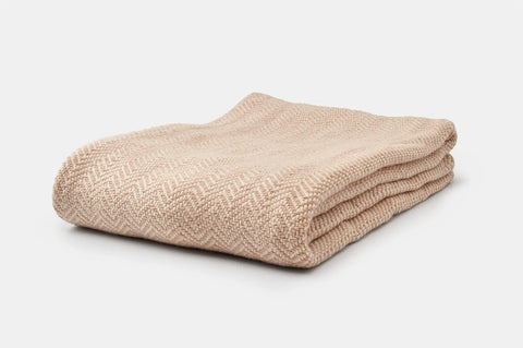 The Chevron Pattern Soft Wool Throw Size Blanket by American Blossom Linens is neatly folded, showcasing its beige color and subtle chevron design, made from Climate Beneficial wool, and placed on a plain white background.