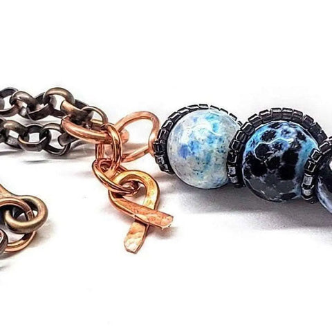 Close-up of the Alexa Martha Designs Child Abuse Prevention Awareness Beaded Gemstone Stick Pendant With Lava Rock Bead Charm Necklace on a white background.