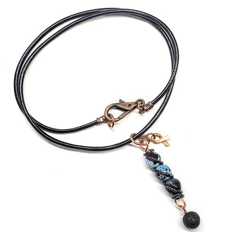 The Alexa Martha Designs Child Abuse Prevention Awareness Beaded Gemstone Stick Pendant Necklace features blue and black gemstone beads, a lava rock bead charm, copper accents, and a leather cord with a copper lobster clasp.