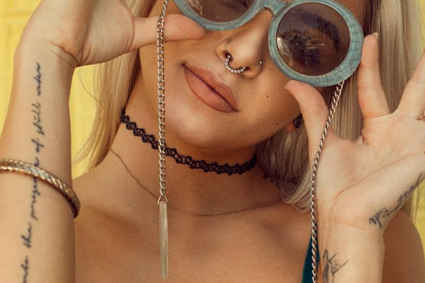 Person wearing sunglasses and a necklace with a yellow background