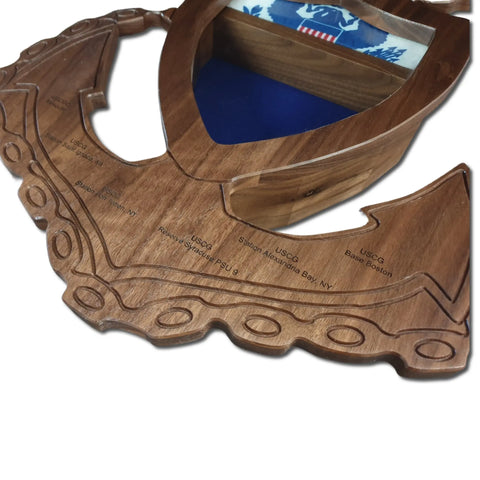 The Coast Guard MCPO Anchor Shadow Box by Legacies of America Woodworking Company is a hardwood plaque shaped like an anchor, engraved at the edges, with a compartment for a folded US flag featuring the Coast Guard emblem. Built by veterans.