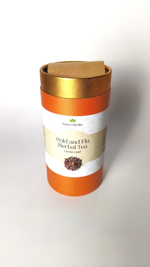 A cylindrical orange and gold container labeled Cold and Flu Herbal Tea by Forev'Herbs, with an image of tea leaves, sits on a white surface—ideal as an immune-boosting tea for cold relief.