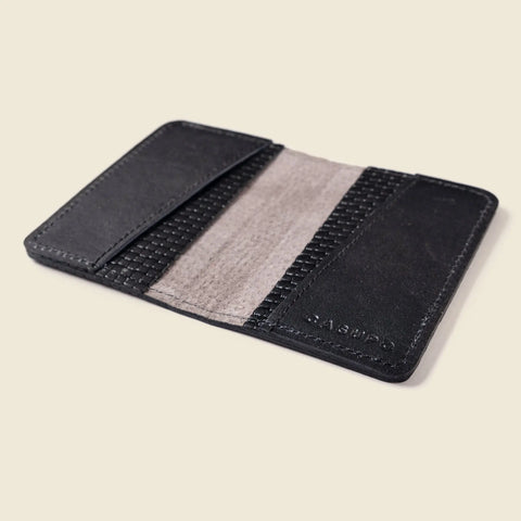 The CASUPO Compact Bifold With RFID Protection - Black Limited Edition is a handcrafted Italian leather wallet with two side pockets and a fabric-lined center, shown open on a beige background.