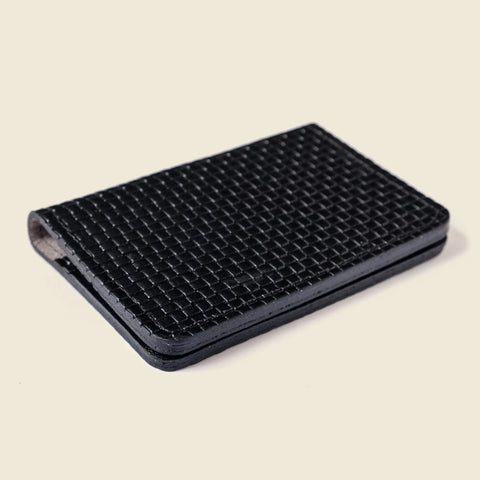 The CASUPO Compact Bifold With RFID Protection - Black Limited Edition, featuring a textured woven pattern, rests closed on a light beige surface.