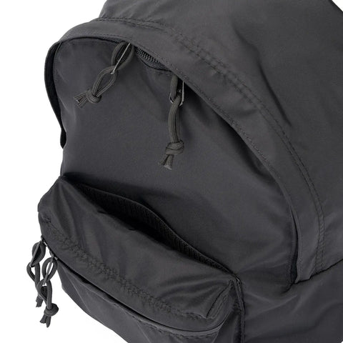 A close-up of the MIS Daypack S - Black, made in USA from water-resistant nylon, displays the top main compartment and front pocket with visible knotted black cord zipper pulls.