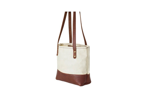 The Urban Southern Mini Canvas Tote features a cream upper, brown leather base and straps, plus gold rivet accents for style and function—a chic, compact bag for everyday use.