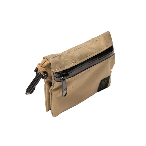 The MIS W Small Pouch in Coyote Tan is a compact, water-resistant nylon pouch with a black zipper, clip, and rectangular black patch on the lower front. It’s displayed at an angle on a white background.