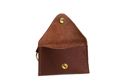 The Urban Southern Keychain Coin Purse is a small brown accessory made from full-grain leather, featuring a flap with brass snap closure, single compartment, and an attached metal key ring for convenient use as a keychain.