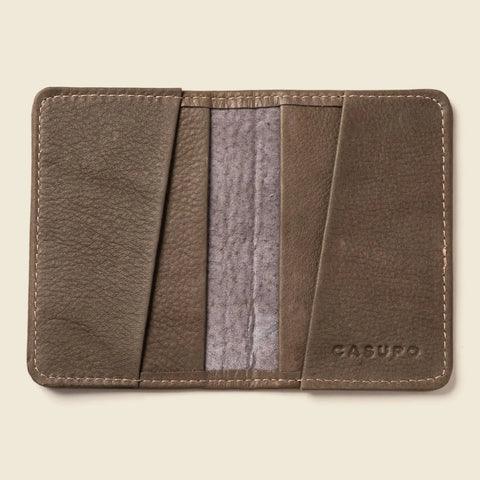 The CASUPO Compact Bifold With RFID Protection – Grey is a sustainable leather wallet featuring stitched edges, two angled card slots per side, the brand name embossed on the bottom right, and a contrasting light gray suede interior.