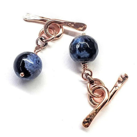 A pair of Copper Child Abuse Prevention Awareness Chain Cufflinks by Alexa Martha Designs, featuring hammered bars and black blue agate beads, connected by gold wire loops, displayed on a white background.