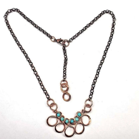 The Alexa Martha Designs As Seen on Ashley Liao Copper Turquoise Wire Wrapped Necklace features a gold loop pendant, five turquoise beads, and a dark metal chain with an S-clasp, beautifully displayed against a white background.