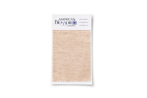 A natural-colored organic cotton Swatch with zigzag edges from American Blossom Linens, attached to a branded card with text details.