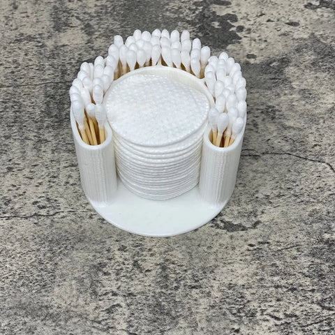 The Chatelet Manufacturing Cotton Swab Bathroom Organizer in clean white keeps Qtips upright around the edge and exfoliating or cotton pads stacked in the center, offering convenient access to your essentials on any bathroom surface.
