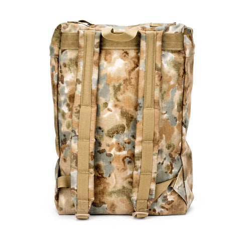 The MIS Backpack - Covert Desert is a camouflage-patterned Cordura Nylon backpack with tan straps and handles, shown upright from the back. It features padded shoulder straps, a rectangular shape, and a padded laptop holder.