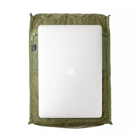 A silver Apple laptop rests on the MIS Backpack - Covert Desert, an olive green, water-resistant padded bag with mesh side pockets, displayed against a white background.
