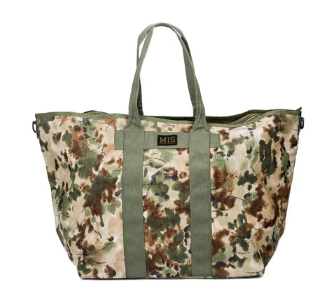 The MIS Super Tote Bag - Covert Woodland is made in the USA from water-resistant Cordura Nylon with green handles and trim, a camouflage pattern in green, brown, and beige, and features a black MIS label with yellow lettering at the center.