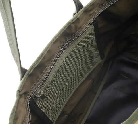Close-up of the interior of the MIS Super Tote Bag - Covert Woodland, made in USA from water-resistant olive green Cordura Nylon, showing a zippered mesh pocket, dark lining, and sturdy handles with reinforced stitching.