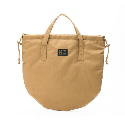 The MIS UK Helmet Bag in Coyote Brown is a rounded tote made from 500D Cordura Nylon, featuring short handles, side drawstrings, a black MIS patch on the front, and water-resistant construction, shown on a plain white background.