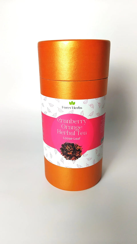 An orange cylindrical container labeled Cranberry Orange Herbal Tea by Forev'Herbs, a caffeine-free loose-leaf herbal tea with a white and pink label featuring leaves and loose tea.