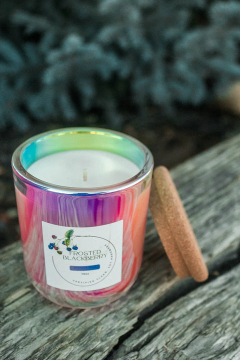 The Cruel Summer Scented Soy Candle by Shanti + Tula comes in a 10 oz prism glass jar with a cork lid, features a Frosted Blackberry label with blackberry and leaf illustrations, and is made from eco-conscious soy wax.