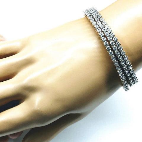 A lifelike mannequin hand displays two Alexa Martha Designs Wire Wrapped Crystal Rhinestone Tennis Bracelet Bangles adorned with clear round gemstones against a white background.